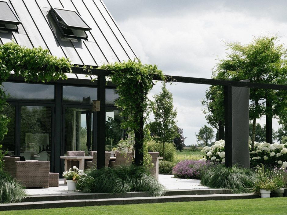 Zwarte pergola accentueert het terras bij de moderne schuurwoning